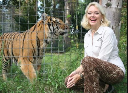 Carole Baskin Net Worth: Carole Baskin in a white t-shirt poses with a tiger.